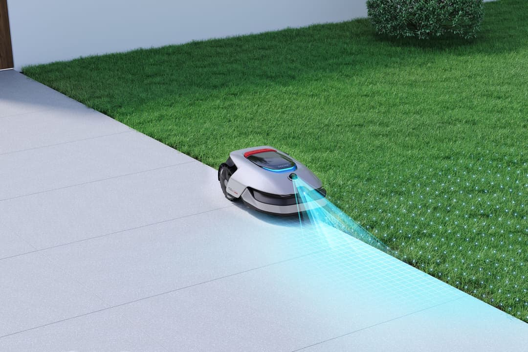 Robot de tonte Dreame A2 blanc et noir tondeuse l'herbe près d'une bordure, avec un faisceau lumineux cyan montrant sa portée de coupe