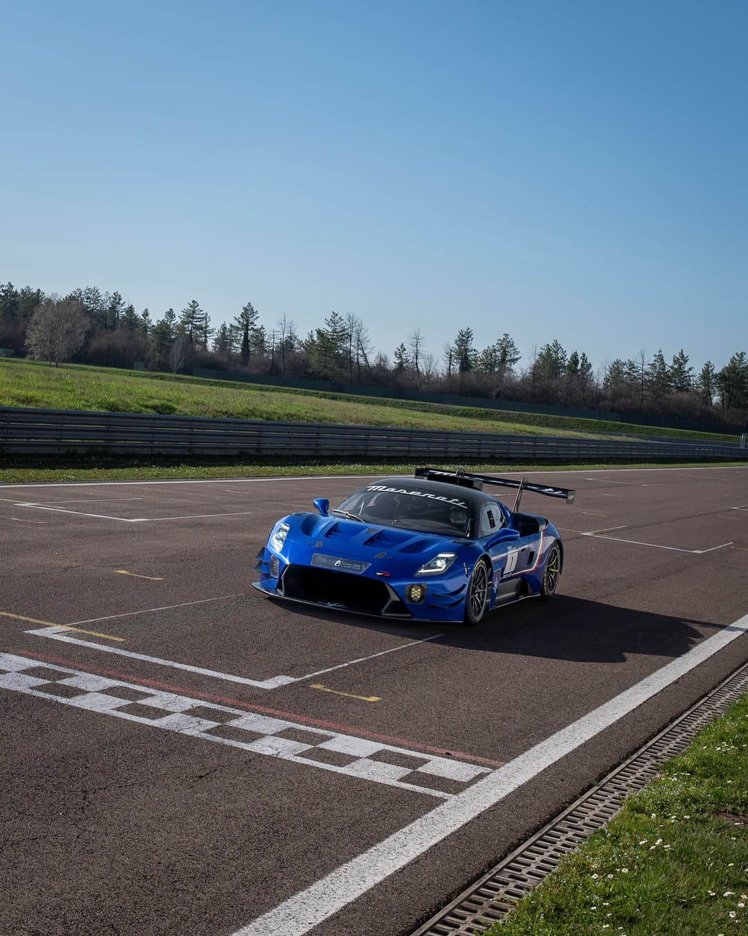 Maserati GT2 bleue équipée d'un aileron sur circuit de course, vue de trois quarts