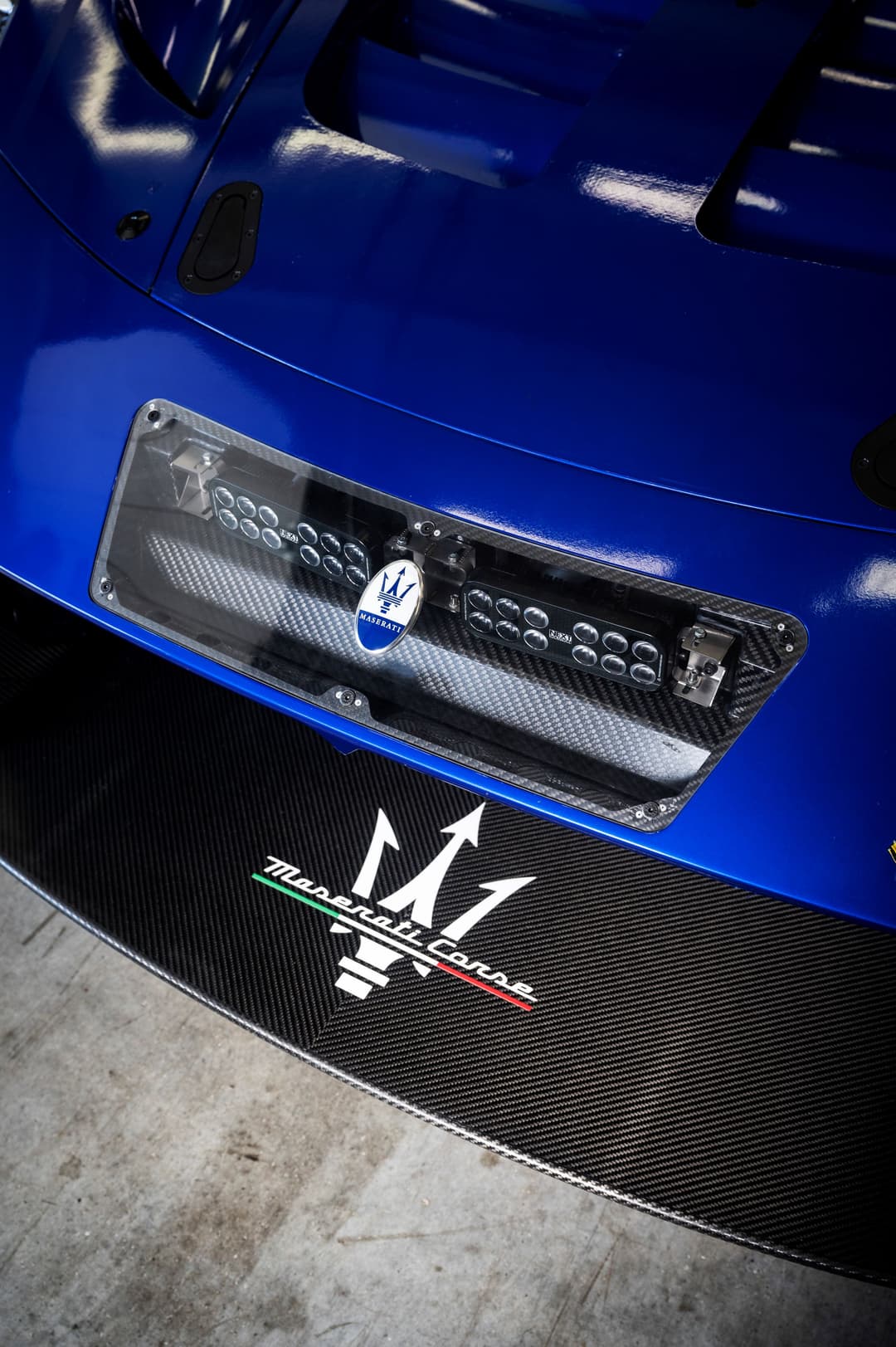 Détail de l'avant d'une Maserati GT2 bleu électrique avec panneau de numérotation électroluminescent blanc sur la porte
