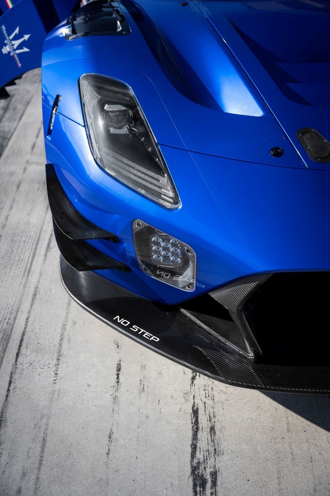 Maserati GT2 bleu électrique, détail du capot, des phares et de l'aileron avant carbone avec inscription « NO STEP »