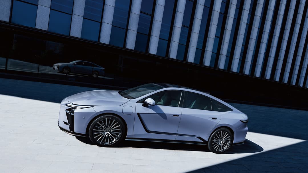Lexus ES blanche avec portière ouverte, stationnée devant une façade de verre et acier moderne