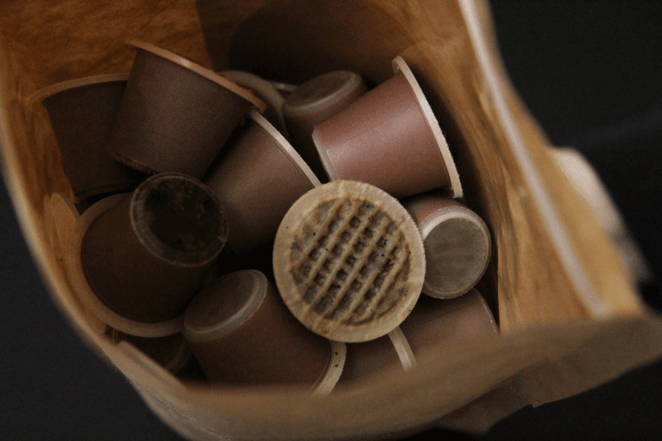 Capsules de café compostables marron dans un emballage en carton, avec un gros plan montrant le relief texturé d'une capsule