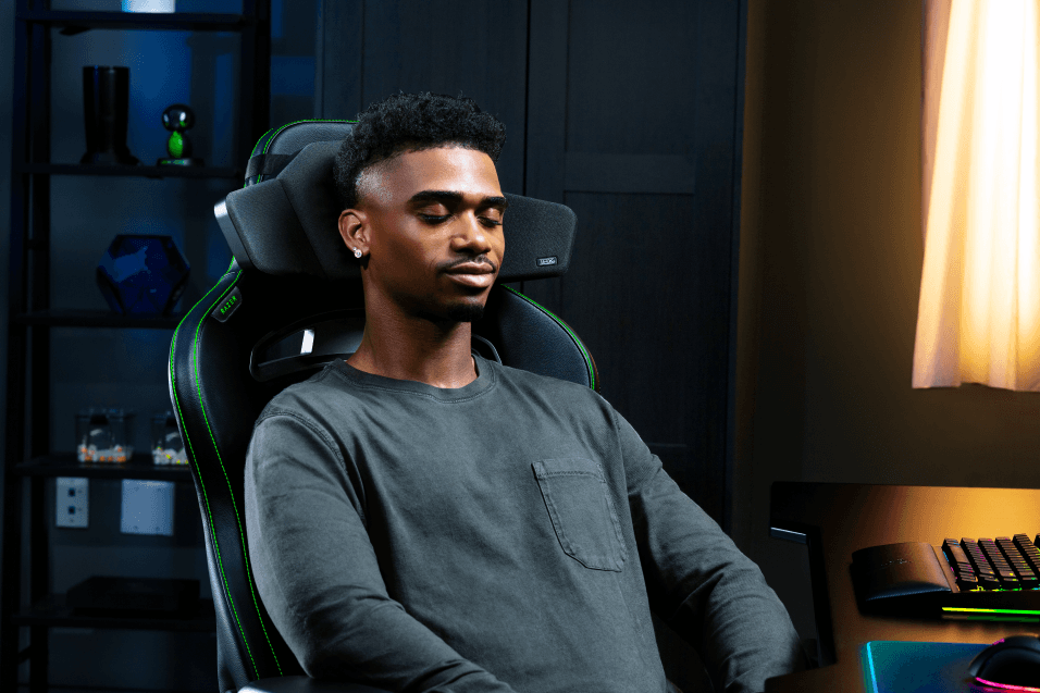 Razer Clio fixé au dossier d'une chaise gaming noire avec bordures vertes, porté par un joueur assis dans un bureau gaming