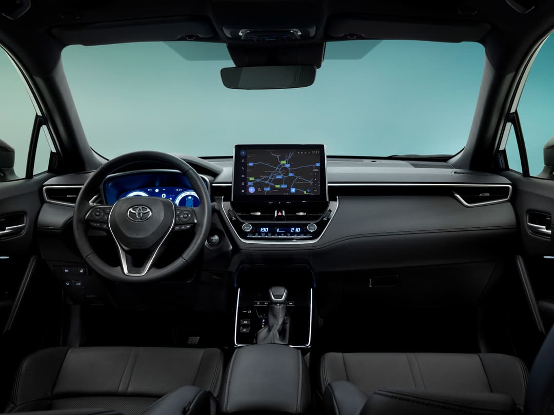 Intérieur du Toyota Corolla Cross avec tableau de bord moderne, écran tactile affichant une carte de navigation et volant noir