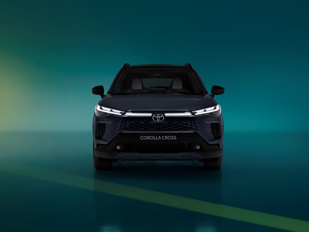 Toyota Corolla Cross noir de face sur fond dégradé bleu-vert, affichant sa nouvelle calandre et ses phares LED