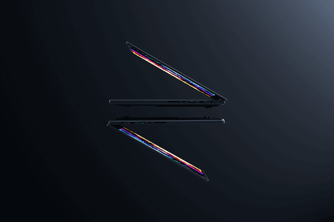 Deux Razer Blade 14 noirs ultra-fins de profil, fermés, affichant leurs bords colorés arc-en-ciel sur fond sombre
