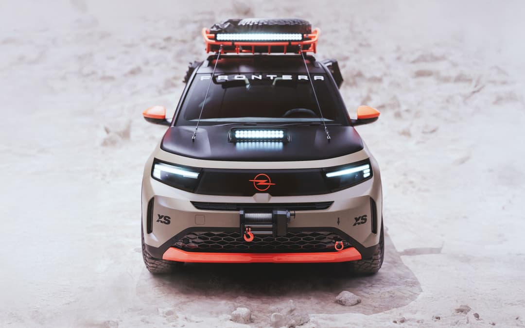 Opel Frontera GRAVEL vue de face, SUV aux accents orange vif, équipé d'une barre LED et d'un porte-charge sur le toit, dans un décor désertique