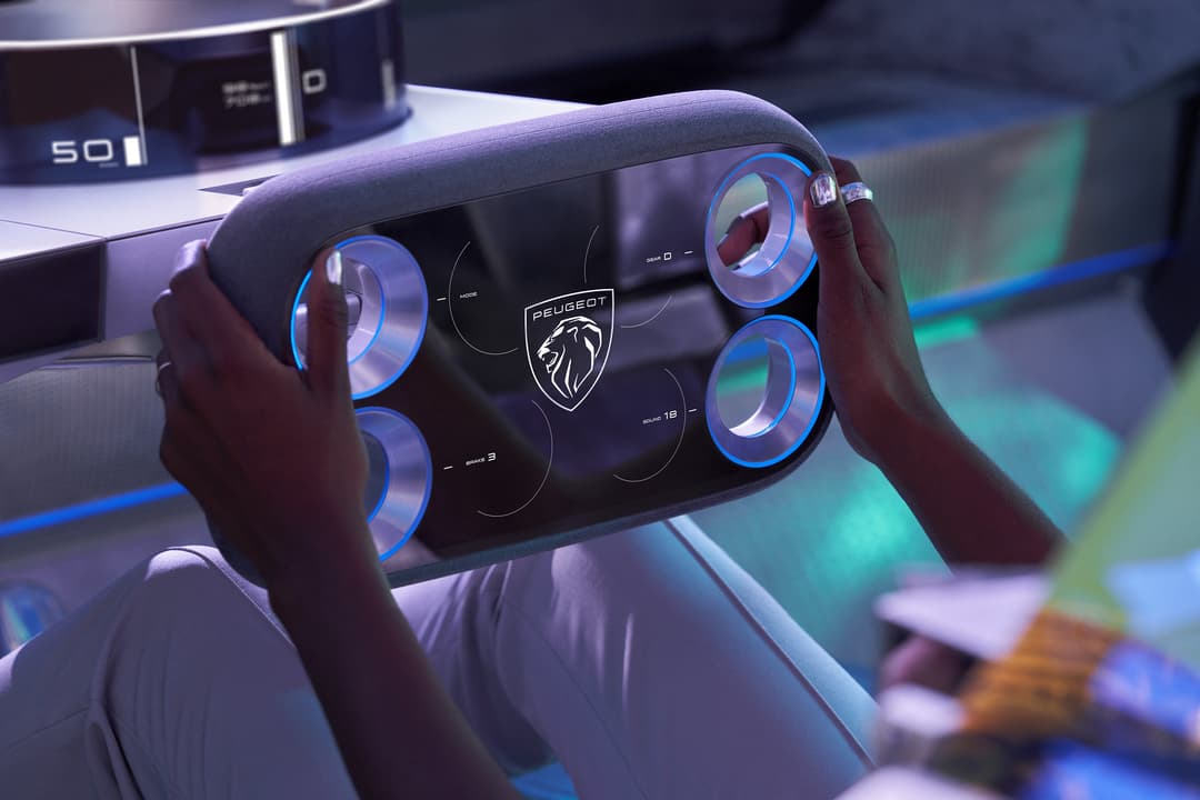 Volant connecté du Hypersquare PEUGEOT avec écrans bleus lumineux intégrés, tenu par deux mains dans l'habitacle du véhicule