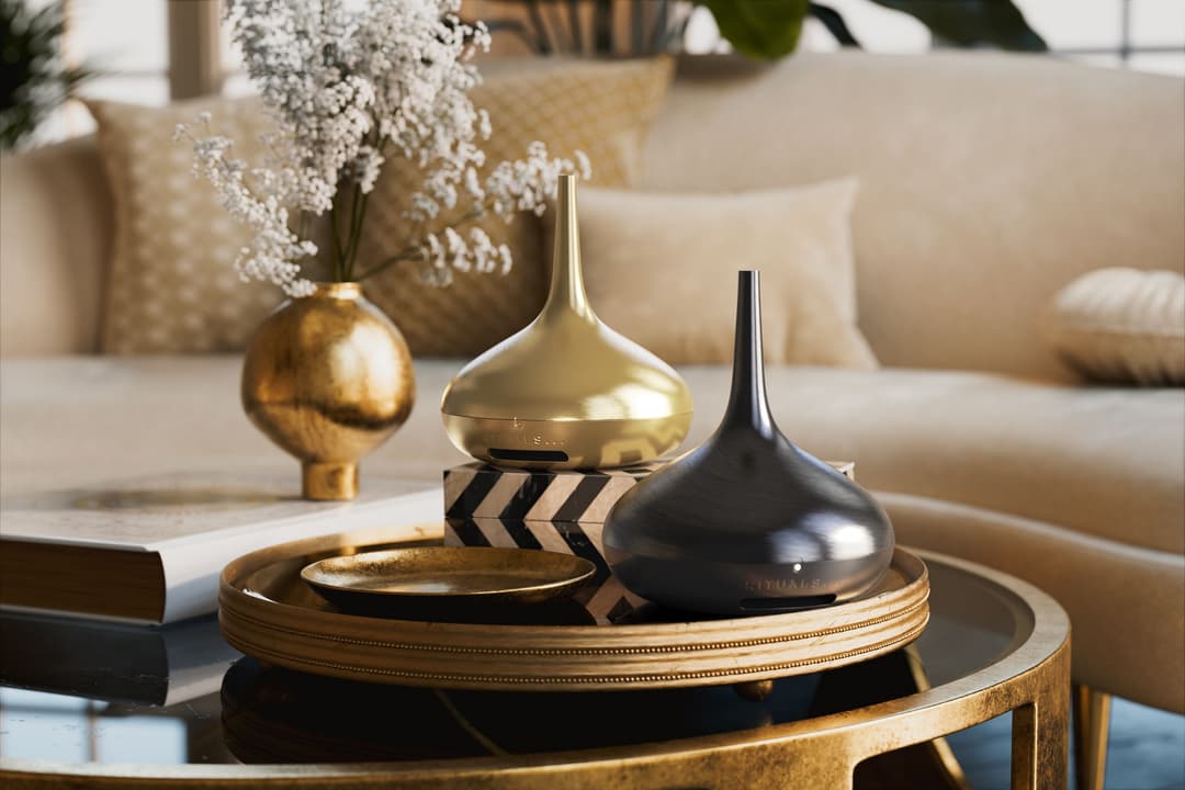 The Perfume Genie 2.0 de Rituals, diffuseur noir et doré sur table basse, entouré de décoration intérieure épurée et minimaliste