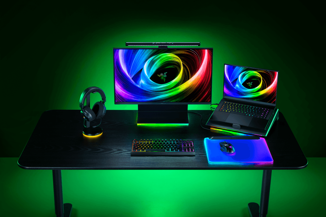 Ensemble gaming Razer avec clavier custom, écrans, casque et souris RGB sur un bureau noir aux contours verts