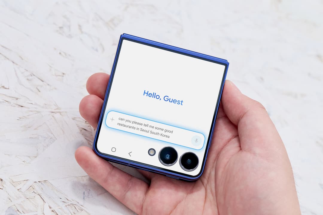 Samsung Galaxy Z Flip7 bleu ouvert dans une main, affichant l'assistant IA avec "Hello, Guest" et une demande de restaurants à Séoul