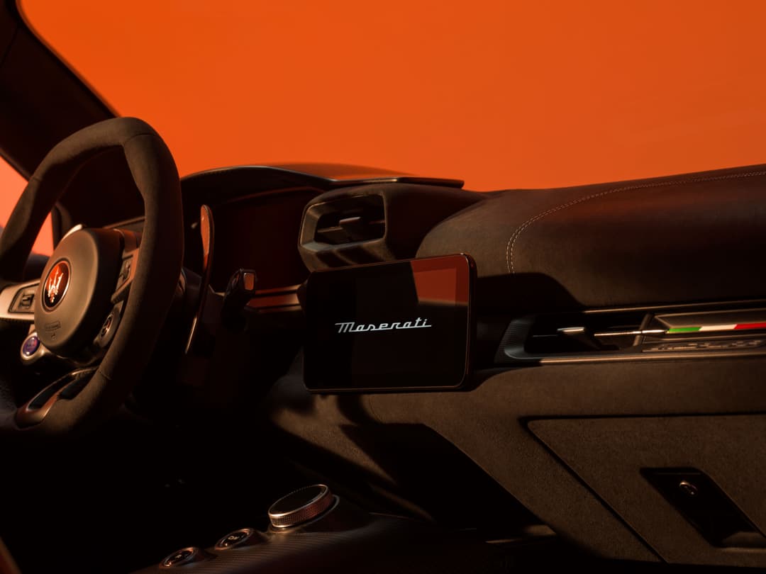 Habitacle de la Maserati MCPURA avec volant Alcantara, écran central noir et détails en cuir sur fond orange