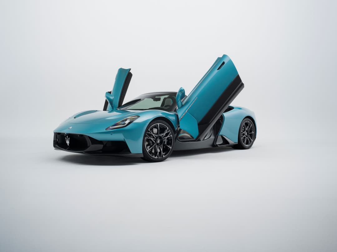 Maserati MC20 PURA bleu turquoise avec portes papillon ouvertes, carrosserie en fibre de carbone, sur fond gris clair