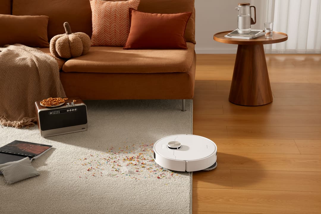 Aspirateur robot blanc Dreame X50 Ultra Complete franchissant la transition entre un tapis et un parquet en bois dans un salon