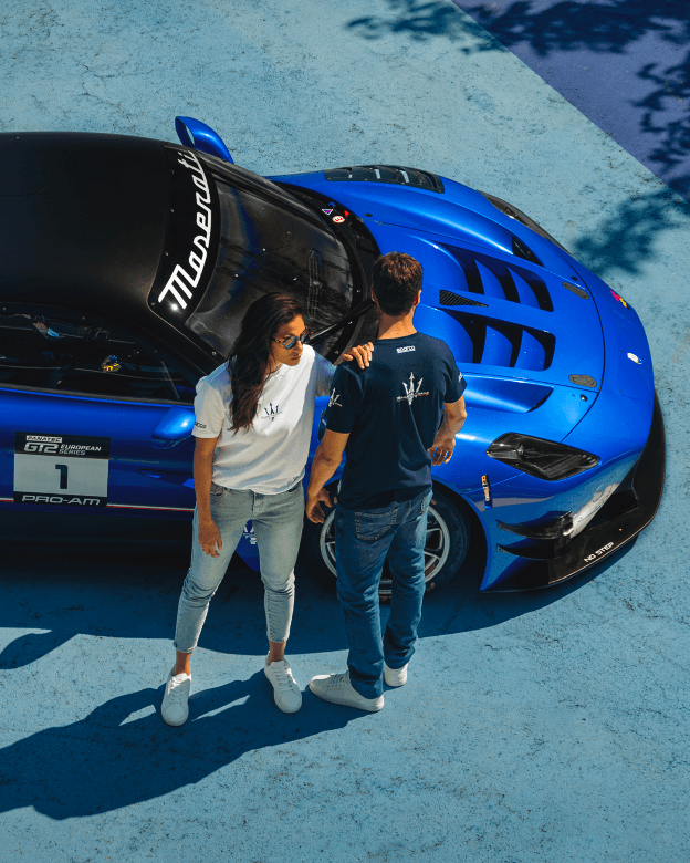 Deux personnes portant des vêtements Sparco X Maserati devant une Maserati bleue vue de dessus