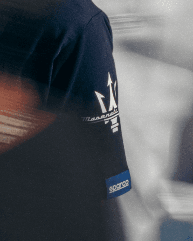 Détail d'une veste bleu foncé Maserati avec logo de la marque et étiquette Sparco bleu sur la manche