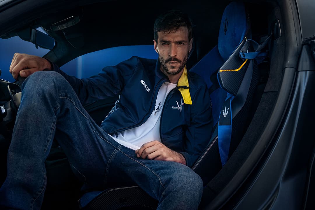 Homme assis dans habitacle de Maserati, vêtu de vêtements Sparco X Maserati bleu marine et jaune avec accessoires assortis