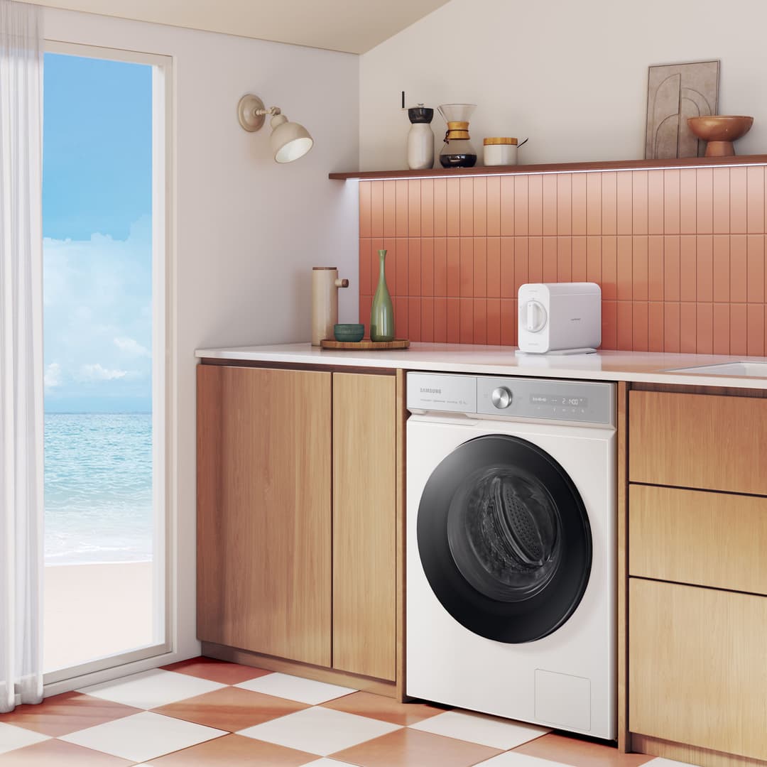Machine à laver Samsung blanche avec hublot noir intégrée dans une salle de bain moderne face à la mer