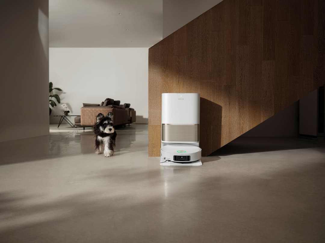 Aspirateur robot Dreame L50 Pro Ultra blanc et métal avec sa station de base, dans un intérieur moderne auprès d'un chien