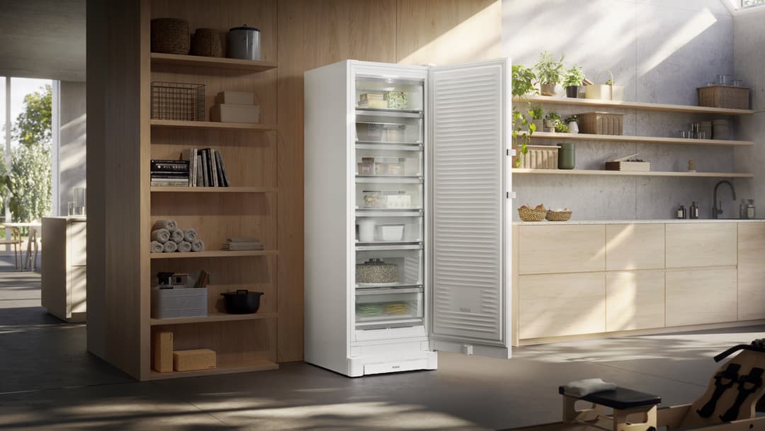 Congélateur Liebherr FNXa 522i blanc aux portes ouvertes, intégré dans une cuisine épurée aux finitions bois clair et béton