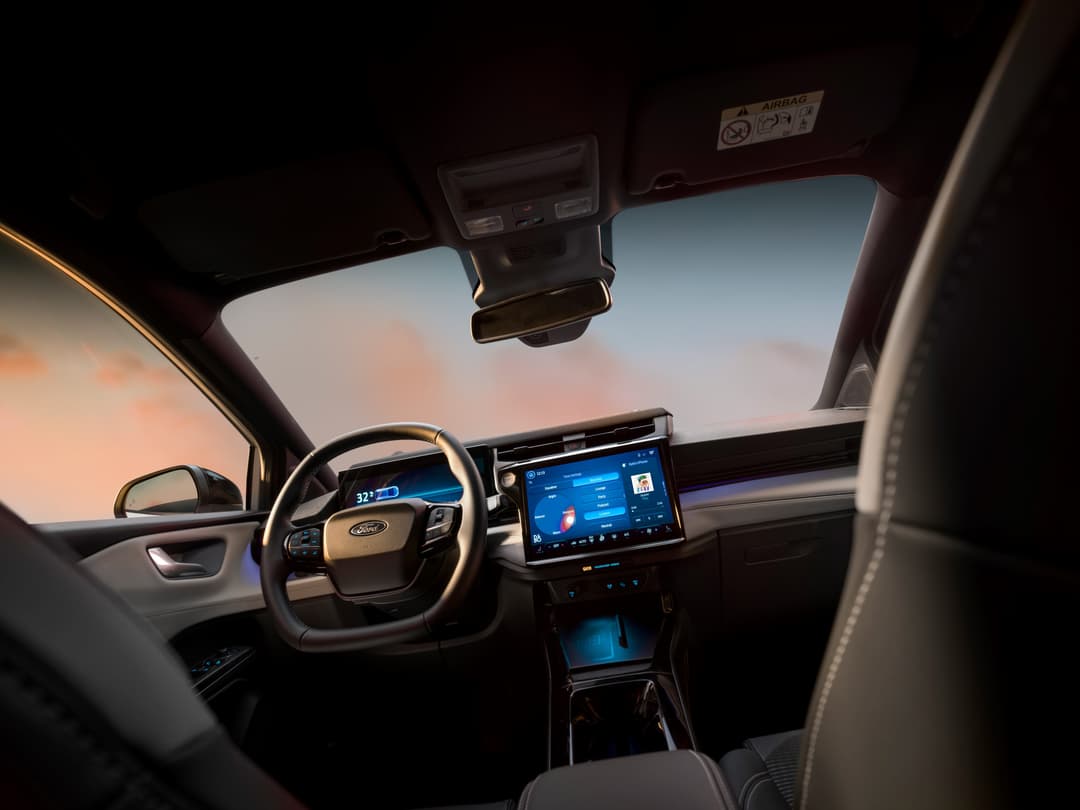Intérieur du Ford Puma Sound Edition avec volant, écran tactile bleu et ciel coucher de soleil visible par le toit ouvrant