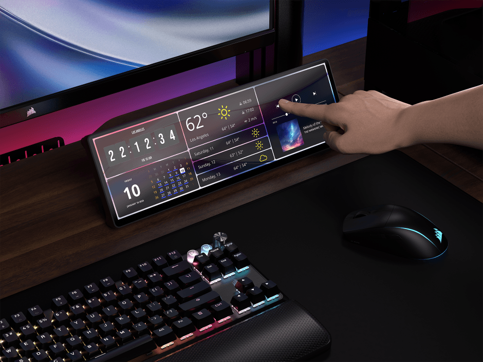 Écran tactile CORSAIR XENEON EDGE affichant horloge, météo et calendrier, avec une main le contrôlant, connecté à un clavier et souris gamer