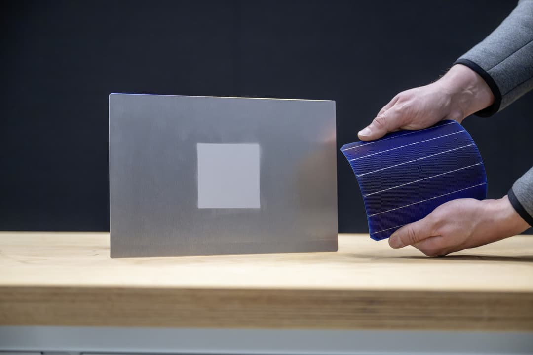 Main tenant un matériau bleu texturé à côté d'une plaque grise, démontrant un substitut de cuir écologique pour automobiles