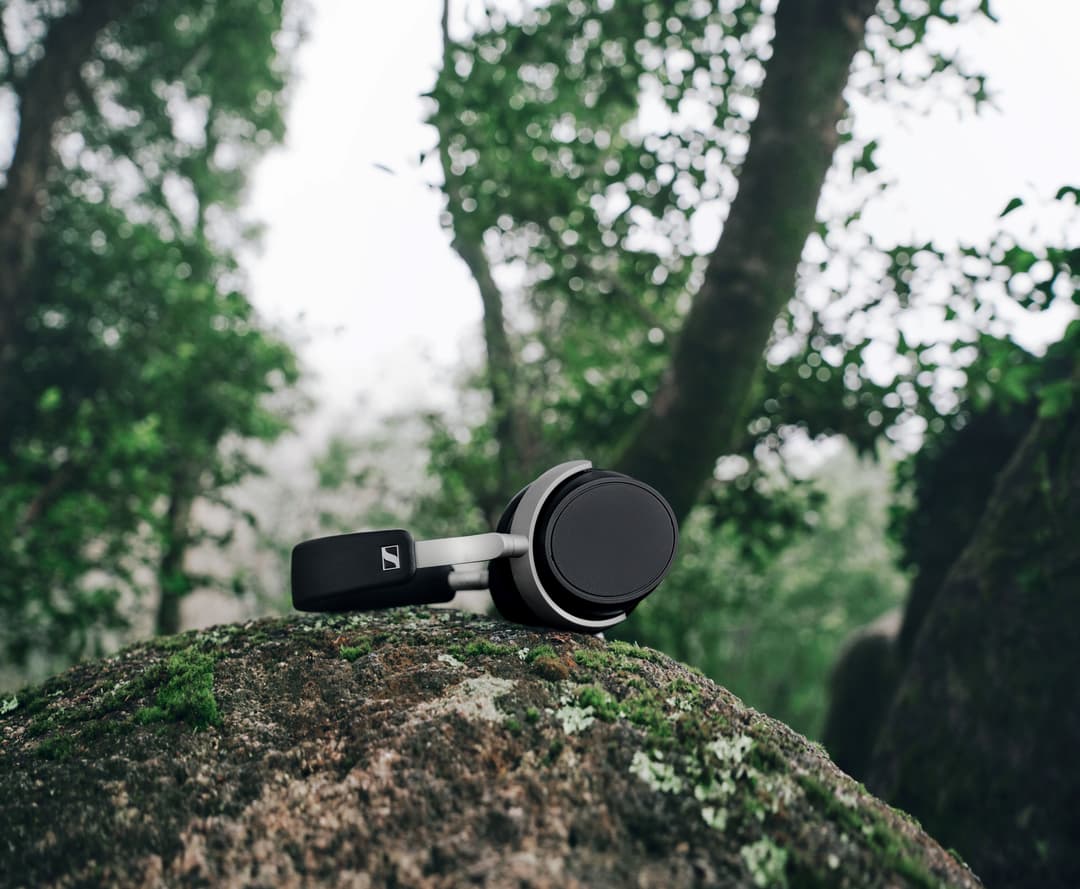 Casque audio Sennheiser noir et blanc posé sur une pierre mousseuse en forêt