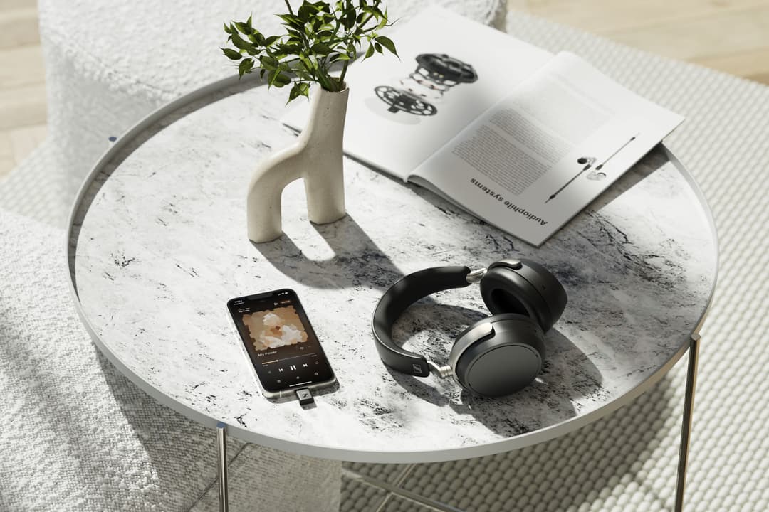 Casque Sennheiser HDB 630 noir posé sur une table blanche, à côté d'un smartphone et d'une revue
