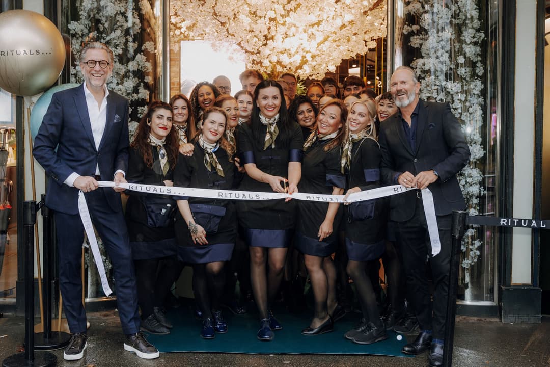 Équipe Rituals coupant le ruban blanc lors de l'inauguration du Mind Oasis à Zurich, devant la devanture décorée de fleurs blanches