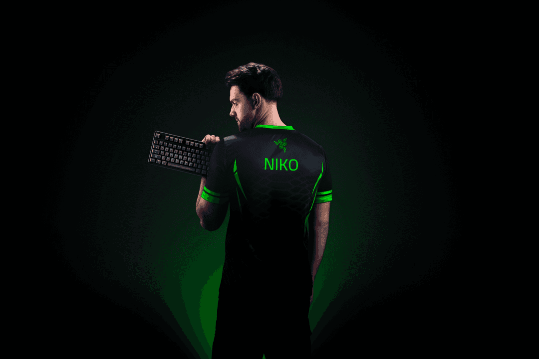 NiKo portant un t-shirt Razer noir et vert tient un clavier Huntsman V3 Pro, fond noir avec dégradé vert