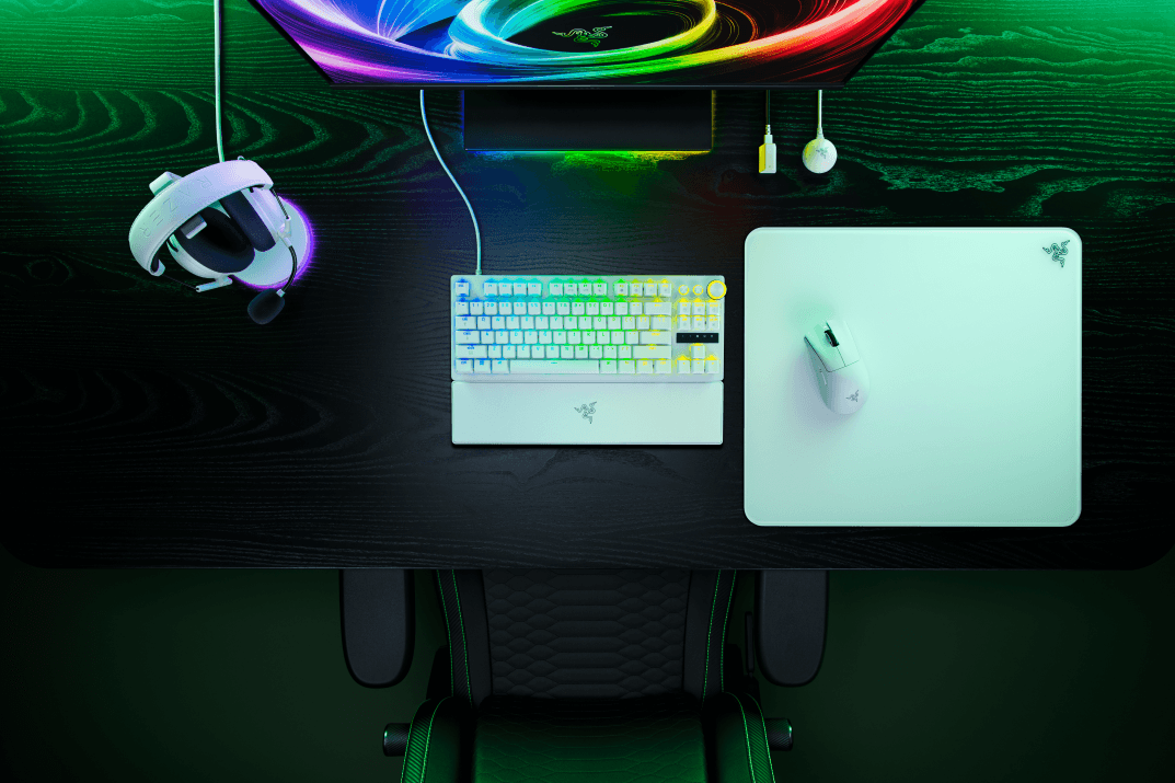 Clavier blanc Razer Huntsman V3 Pro, souris blanche, tapis mint et casque blanc avec éclairage RGB multicolore sur un bureau gaming