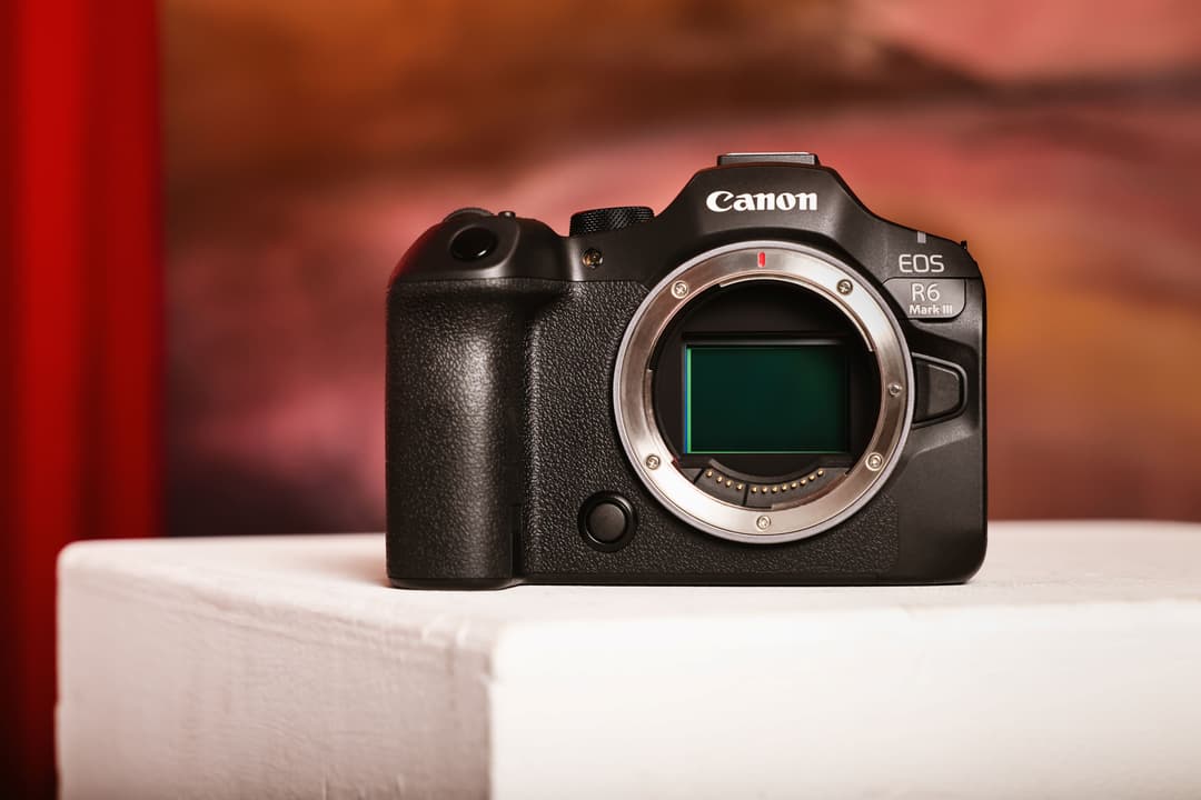 Boîtier Canon EOS R6 Mark III noir, sans objectif, posé sur fond blanc avec arrière-plan dégradé rouge et orange