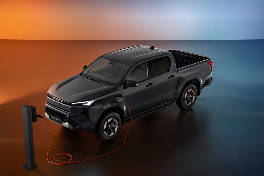 Toyota Hilux neuvième génération noir en charge sur borne électrique, fond dégradé orange et bleu