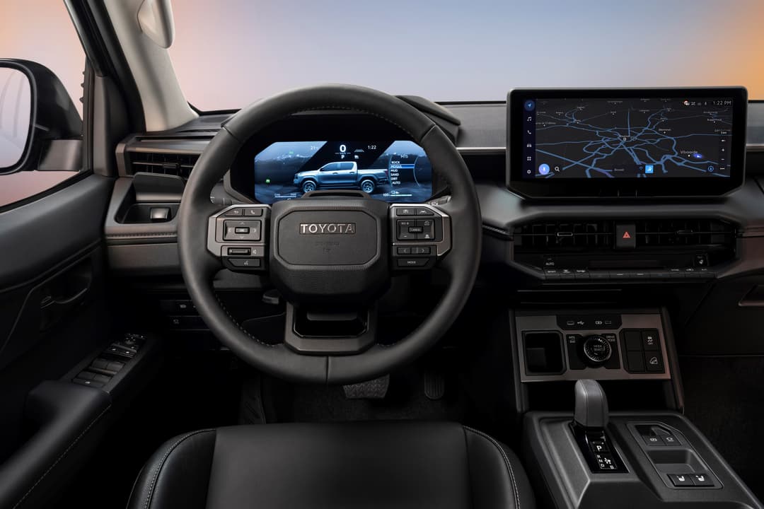 Habitacle du Toyota Hilux neuvième génération avec volant, écran numérique affichant le pick-up et système d'infodivertissement haute résolution