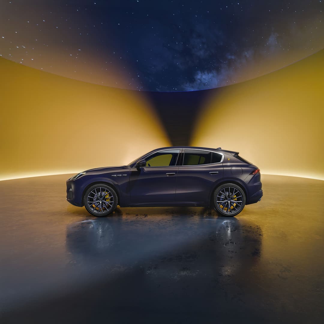 Maserati Grecale Lumina Blu bleu foncé vue de profil dans un environnement surréaliste aux teintes jaunes et bleu nuit
