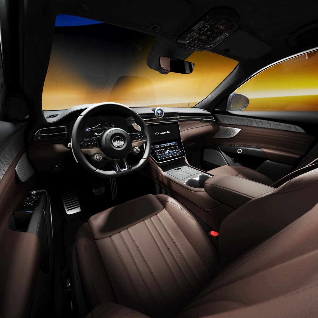 Habitacle du Maserati Grecale Lumina Blu avec cuir Chocolat, volant sportif, bois de ronce et pédalier en acier