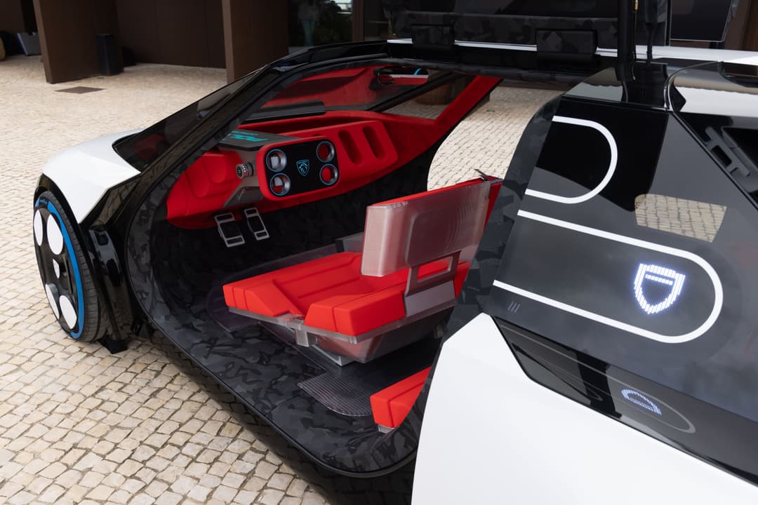 Peugeot Polygon Concept avec portière ouverte, intérieur rouge vif et écran micro-LED visible sur le flanc noir et blanc du véhicule électrique