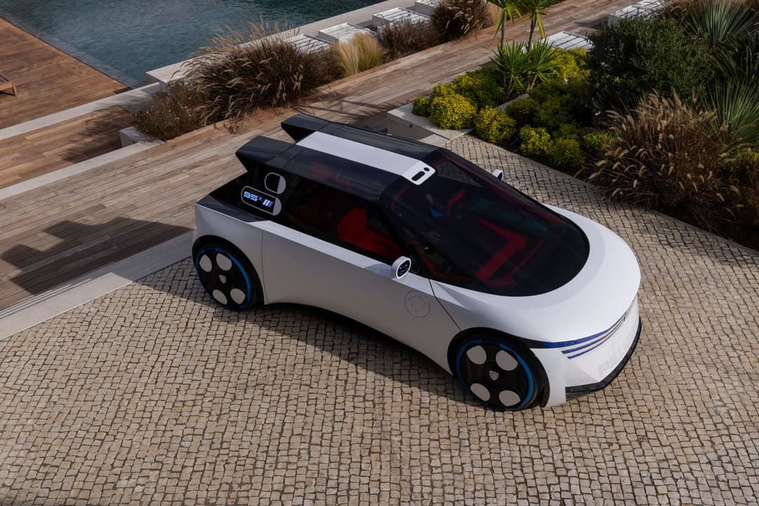 Peugeot Polygon Concept, véhicule électrique blanc et noir aux roues futuristes, stationnée sur un patio en bois près d'une piscine