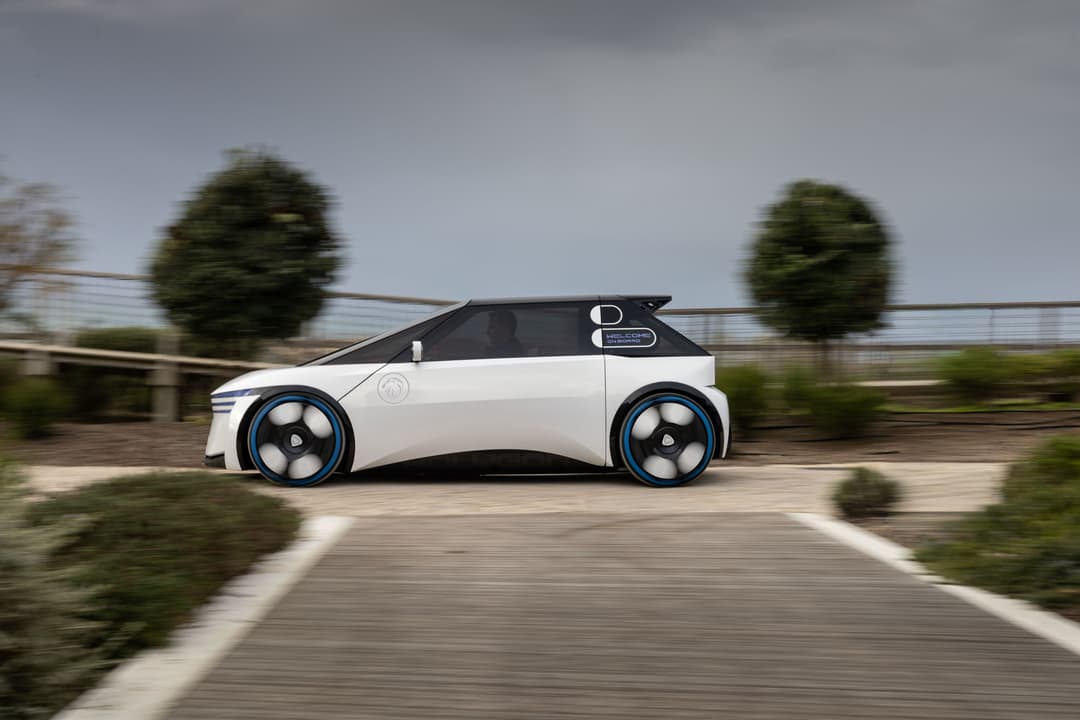 Peugeot Polygon Concept, véhicule électrique blanc et noir aux formes géométriques, roues bleues, roulant sur une route