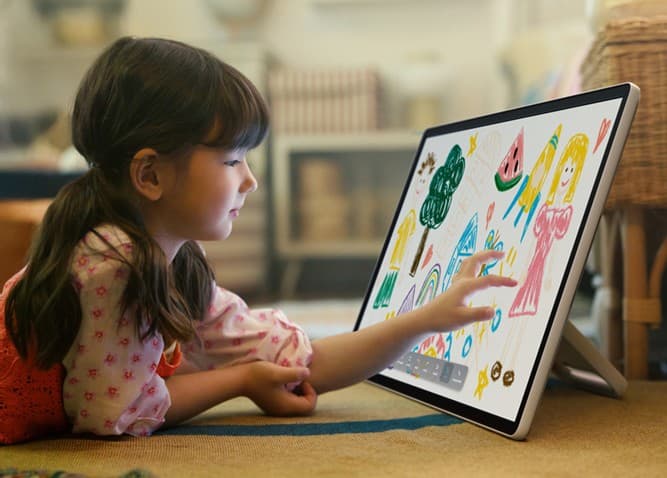 Enfant dessinent sur l'écran tactile d'une tablette Samsung en mode chevalet, avec des croquis colorés visibles à l'écran