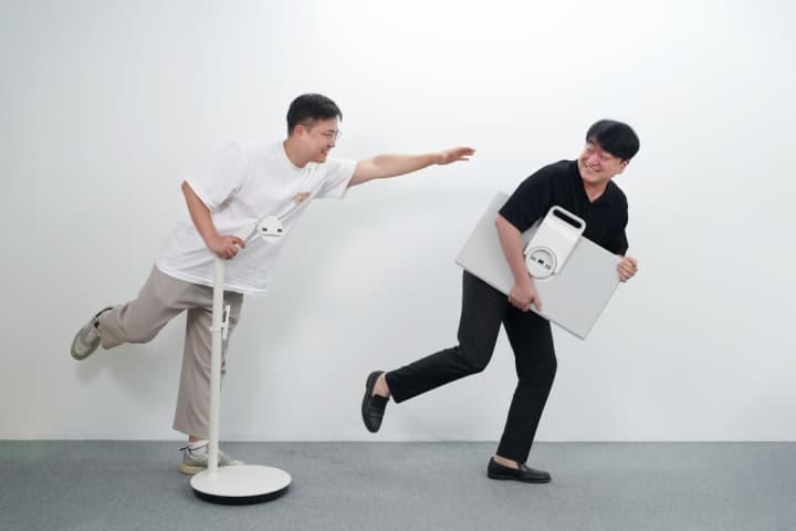 Deux personnes jouent avec le Samsung Movingstyle, un écran portable blanc qu'elles manipulent avec dynamisme et humour
