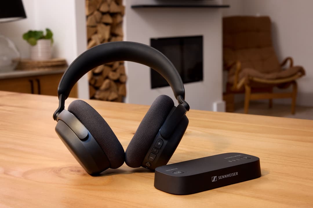 Casque sans fil Sennheiser RS 275 noir posé sur une table en bois avec sa station de base, dans un salon
