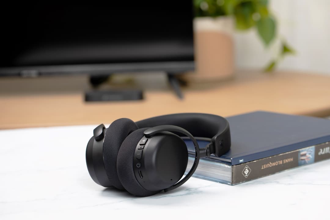 Casque TV Sennheiser RS 275 noir posé sur un bureau blanc, avec un écran TV flou en arrière-plan