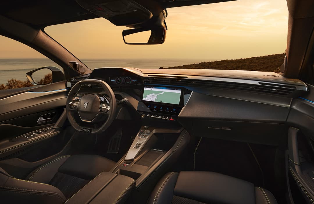 Intérieur de la PEUGEOT 408 avec volant, tableau de bord et écran tactile, vue depuis la mer au coucher de soleil