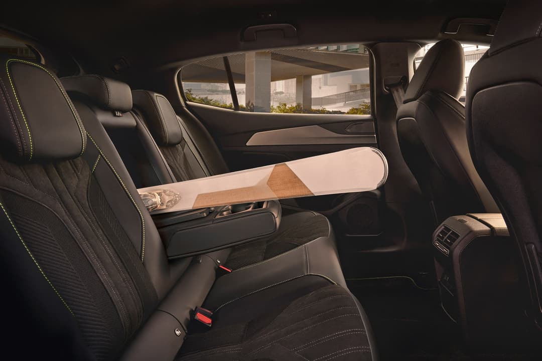 Intérieur de la Peugeot 408 montrant les sièges arrière spacieux avec sellerie noire et surpiqûres jaunes, banquette rabattable et large espace pour les genoux