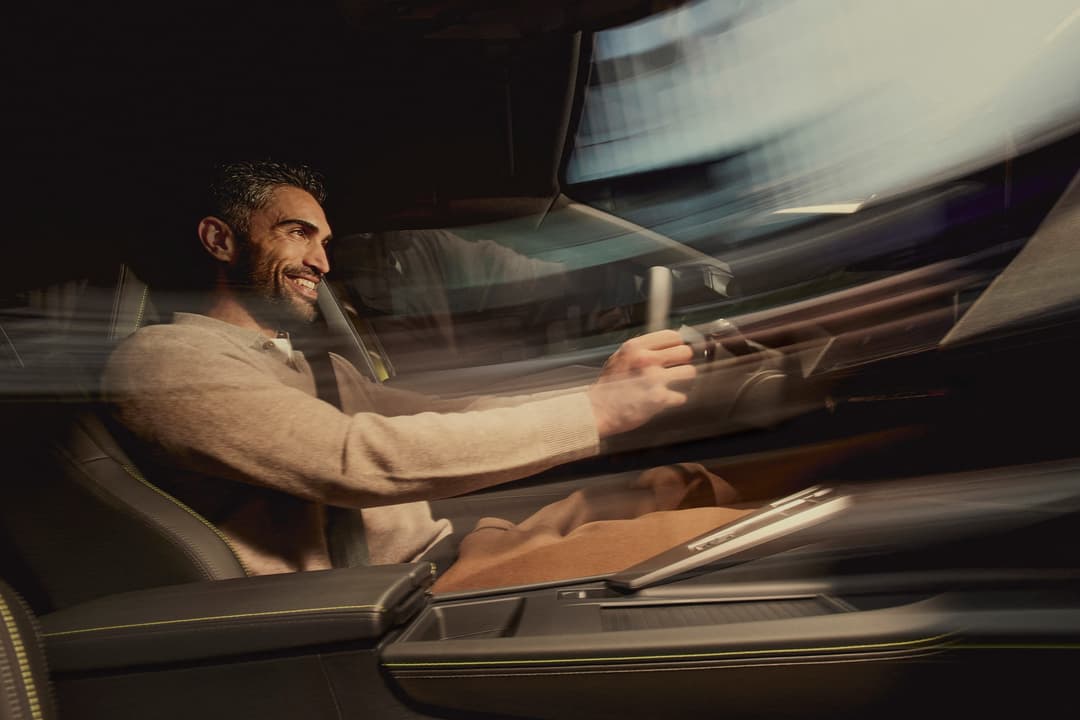 Conducteur souriant au volant de la PEUGEOT 408, intérieur élégant avec écran tactile et système de navigation TomTom connecté