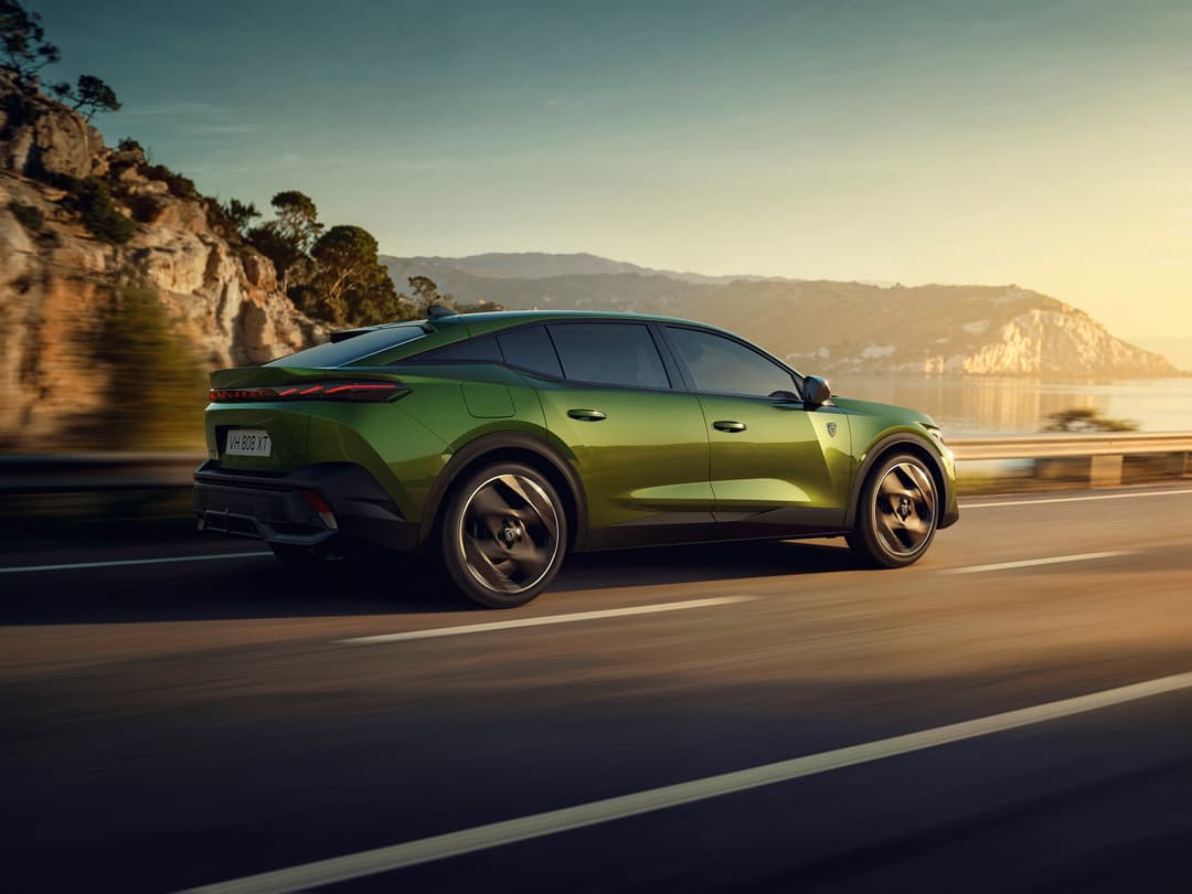 Peugeot 408 verte en mouvement sur une route côtière au coucher du soleil, falaises calcaires en arrière-plan