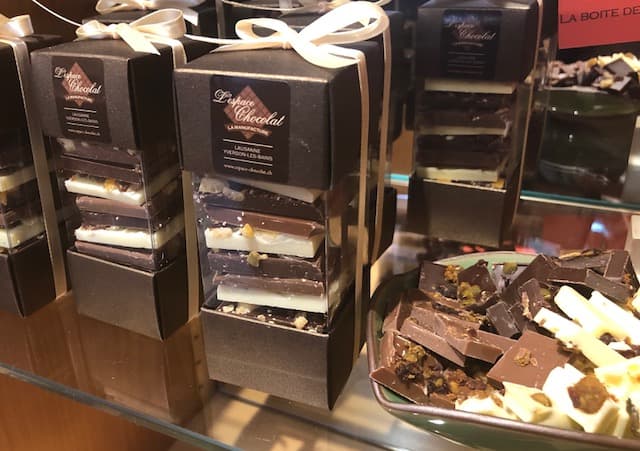 Boîtes noires de chocolats artisanaux Petite Chocolat avec rubans blancs, exposées dans une vitrine de boutique