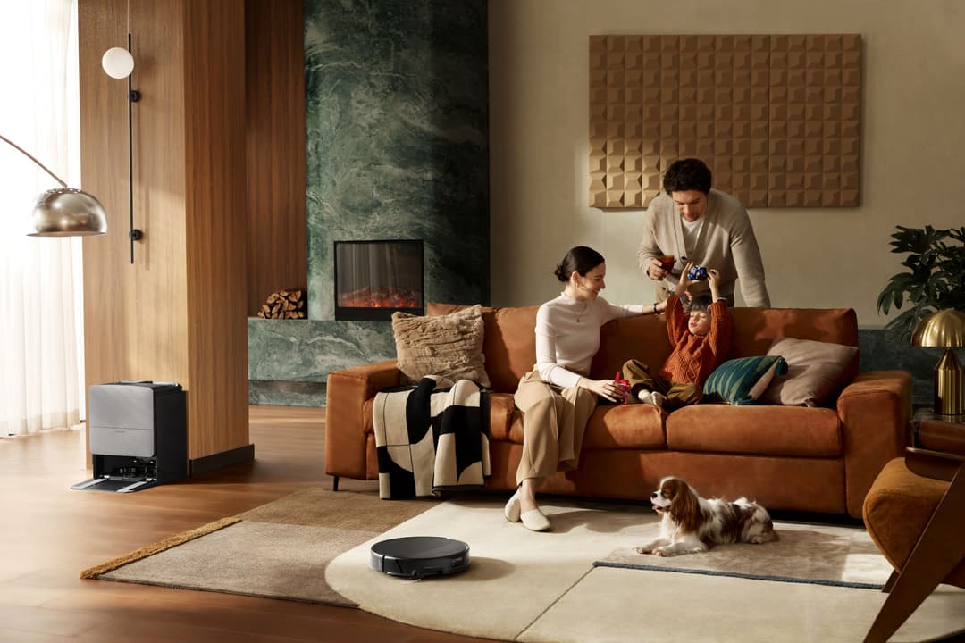 Roborock Saros 20, robot aspirateur noir circulaire, fonctionne dans un salon moderne où une famille joue avec un enfant et un chien